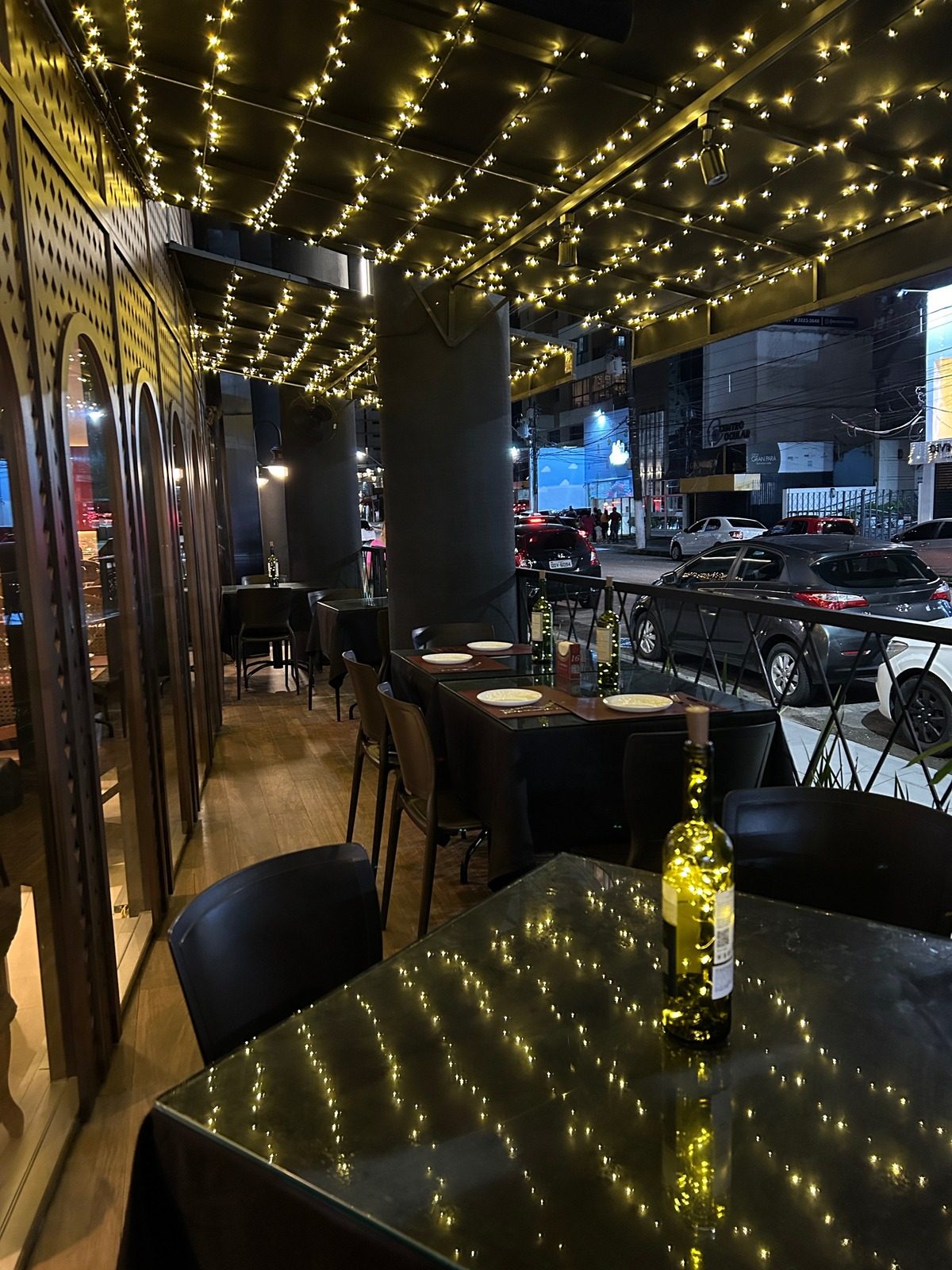 Varanda do Estilo Bistrô à noite, com mesas e cordões de luz